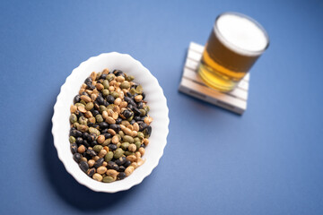 Edamame, toasted soy and draft beer glass on dark blue