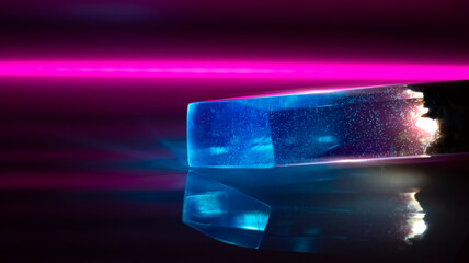 Blue crystal, reflection of neon light on a white glossy surface. Dark neon background.
