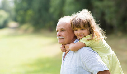 Little child girl hugs grandpa On Walk in the summer outdoors. Concept of friendly family.
 - obrazy, fototapety, plakaty