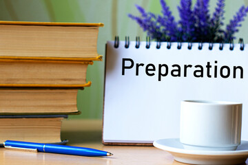 PREPARATION - word in a notebook on a background of old books with pen and white cup