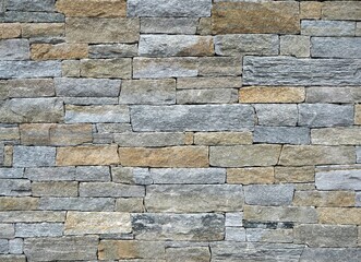 Exterior wall made of different shapes natural stone bricks. Colors are  brown and gray. Background and texture.