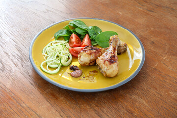 45 degree angle view of Chicken legs roasted with salad tomato spinach and courgette