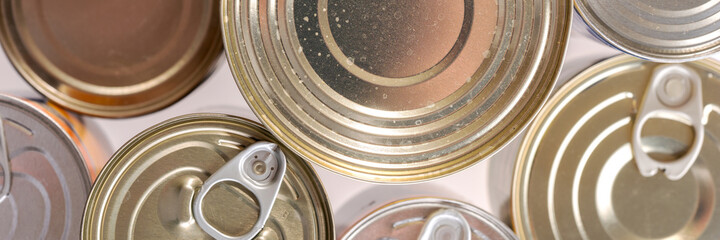 Various canned food in metal cans, top view. Panoramic image