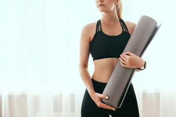 Woman preparing for a workout, holding a fitness mat, close-up