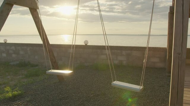 Slow motion, Empty swing set swing, silhouette at sunset.