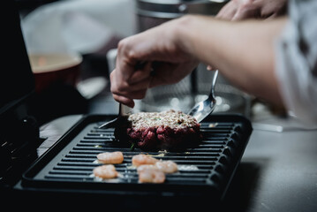 Cocinero cocinando hamburguesa de ternera a la parrilla