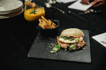 Hamburguesa con huevo frito y patatas fritas servida sobre plato de pizarra