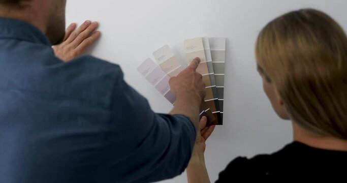 home improvement - young couple choosing paint color from samples for new interior design