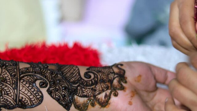 Closeup of Woman designing Henna or Mehendi Tatto on the palm of a girl. Artistic design floral design