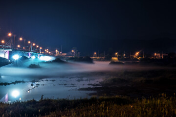 Naklejka na ściany i meble The beautiful dense foggy nightscape with bridge and lanterns light in the night.