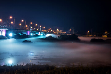 Fototapeta na wymiar The beautiful dense foggy nightscape with bridge and lanterns light in the night.