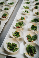 Detalle de catering con platos individuales de ensalada encima de una mesa