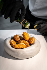 Manos de chef echando aceite de oliva sobre pollo rebozado en plato