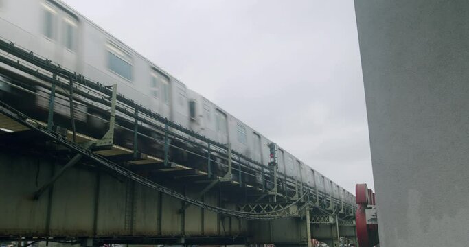 New York City MTA Subway Train Quickly Passes Through Overhead Station on Cloudy Day