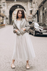 Young girl in white clothes goes on a street. Street style. Soft selective focus.