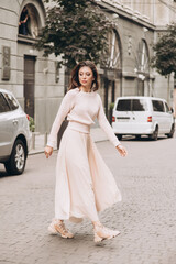 Young girl in white clothes goes on a street. Street style. Soft selective focus.