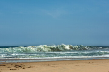 The big breaking waves during a strom at the beautiful summer sea shore background the blue sky and horizon