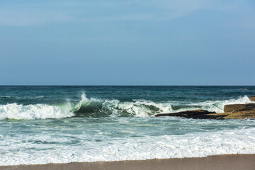 The big breaking waves during a strom at the beautiful summer sea shore background the blue sky and...