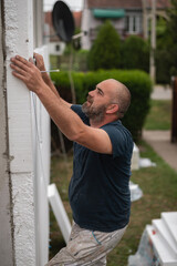 Construction worker working on a house facade checking level of glued boards