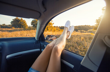 Woman's legs out of the car window. overlooking the beautiful sunset