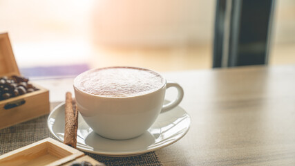 Coffee in a white mug placed on the table with a warm light.