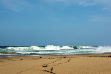 The huge waves crashing into ston island against the blue sky and horizon at summer sea shore.