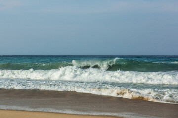 The huge waves crashing into ston island against the blue sky and horizon at summer sea shore.
