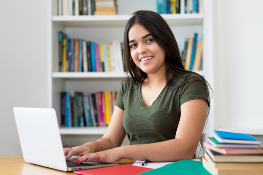 Lachende Schülerin lernt online am Computer zuhause