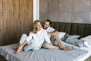 Happy positive loving couple sitting on a bed