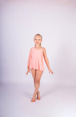 a beautiful gymnast girl in a sports swimsuit stands on a white isolated background and looks at the camera
