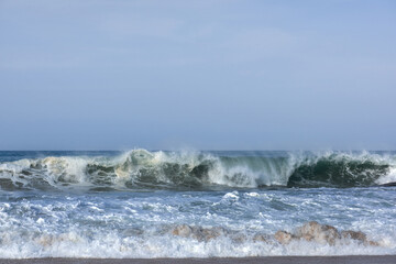 The huge waves crashing into ston island against the blue sky and horizon at summer sea shore.