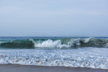 The huge waves crashing into ston island against the blue sky and horizon at summer sea shore.