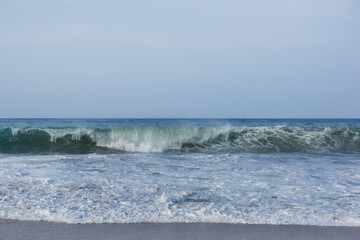 The huge waves crashing into ston island against the blue sky and horizon at summer sea shore.