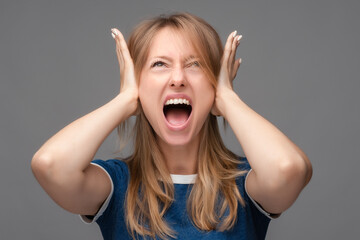 Angry Blonde girl shut ears with hands and screaming. Human emotions, facial expression concept