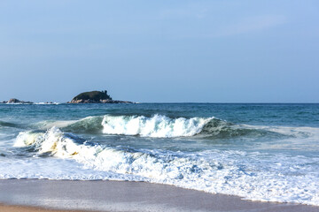 The huge waves crashing into ston island against the blue sky and horizon at summer sea shore.