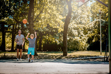 Cute blond boy practicing basketball with his coach