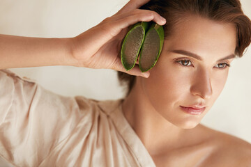 Beauty Face. Woman Holding Slices Of Aloe Vera Leaf And Looking Away. Tender Brunette With Natural...