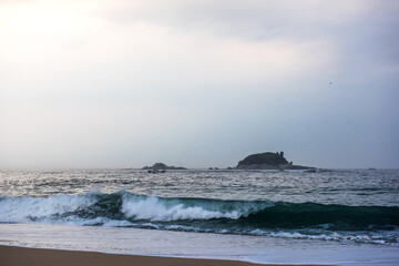 The huge waves crashing into ston island against the blue sky and horizon at summer sea shore.