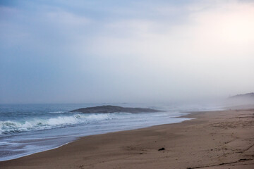 The huge waves crashing into ston island against the blue sky and horizon at summer sea shore.