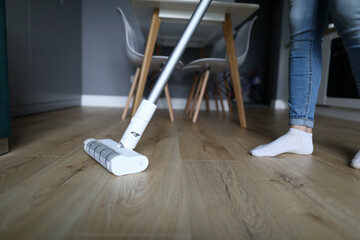 A woman in jeans and socks stands on a laminate in an apartment and washes the floor. Housewife...