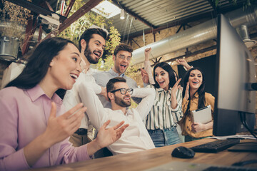 Photo of ecstatic entrepreneurs woman man work computer enjoy raise fists clap hands anti crisis start-up development plan done expert guy stretch hands sit table in workplace workstation