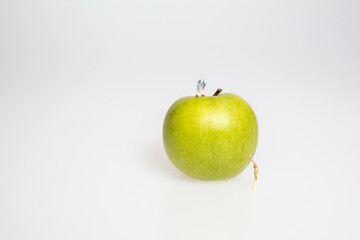Apfel mit Miniaturfiguren auf weißem Grund
