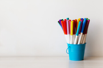 Obraz premium Blue basket with multi-colored felt-tip pens on a white background,copy space