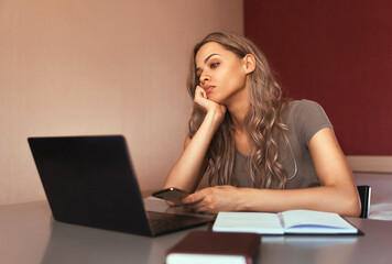 Fototapeta premium Bored mixed race woman working at home using laptop