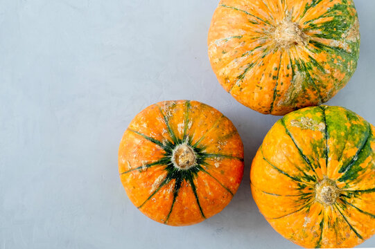 Top view of three ripe variegated pumpkins on a gray surface. Horizontal orientation, selective focus.