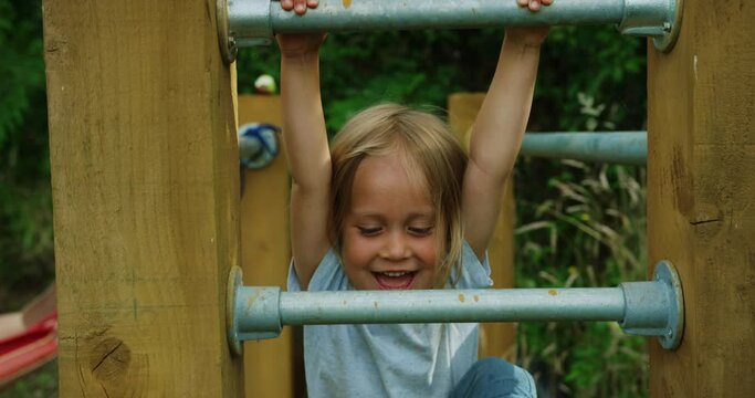 Preschooler climbing and hanging from bars of calisthenics gym