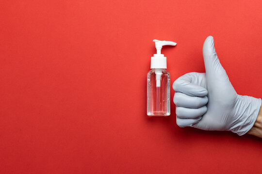 Medical background red. Medical antibacterial sanitizer gel and lab gloves on Virus protection equipment background. Clear sanitizer in pump bottle. Novel Coronavirus 2019-nCoV
