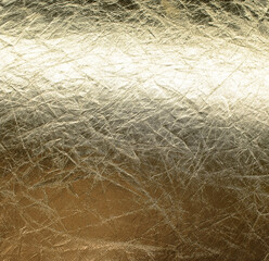 Background of old crumpled gold foil, glossy texture