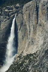 Yosemite waterfalls from taken from above with a strong plum of water flow against the beautiful rock walls, tbeauty of nature and nothing spared