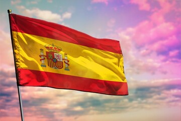 Fluttering Spain flag on colorful cloudy sky background. Prosperity concept.